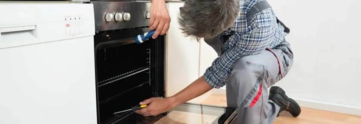 Oven repair technician inspecting and servicing an electric oven in Minneapolis, MN