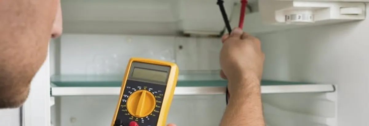 Refrigerator repair technician testing electrical components with a multimeter in Minneapolis, MN